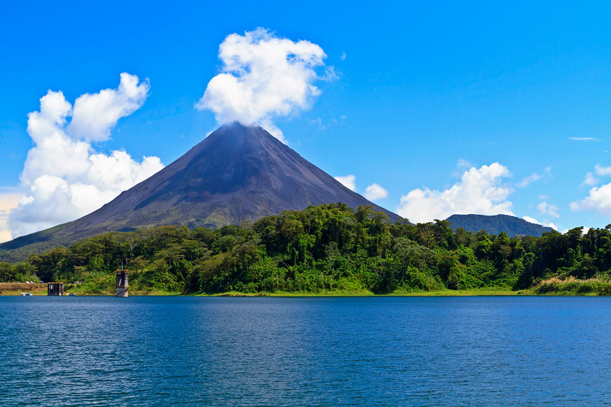 Arenal volcano looms over Lake Arenal on sunny day